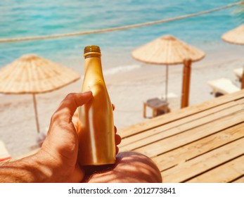 Man drinking bottle of cold beer while resting by the seashore in a hot  summer day.  Summer drink with blurry beach on background. Sunny day on vacation. - Powered by Shutterstock