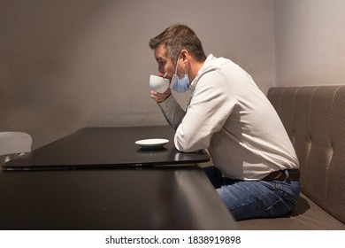 Man drinking coffee in a bar sitting in a white shirt and hygienic mask for the pandemic - Powered by Shutterstock