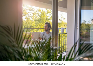 Man drinking coffee on the balcony of his apartment  - Powered by Shutterstock