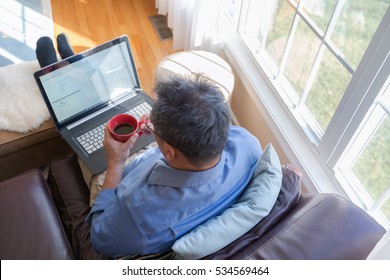 man drinking coffee and working on a laptop at the comfort of his home - Shutterstock ID 534569464