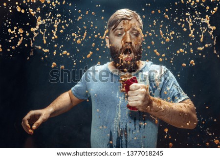 Man drinking a cola at studio. Young smiling happy caucasian guy opening can with cola and enjoying the spray. Advertising image about favourite drink. Lifestyle and human emotions concept.