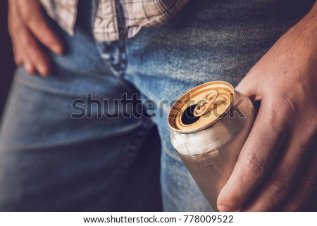 Man drinking a cold beer after work in the evening. Hand holding a aluminum can. Resting time in the bar or pub. Thoughtful atmosphere. Alcohol problem concept.