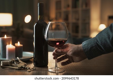 Man drinking a glass or red wine at home, room interior in the background