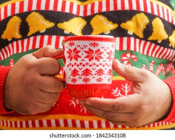 Man Drinking Hot Chocolate. Christmas Tree Pattern. Decorated Drink Mug. Male Wearing Knitted Sweater With Xmas Ornament Holding Hot Coffee In Red Cup. Gay Celebrate Winter Holidays. No Face