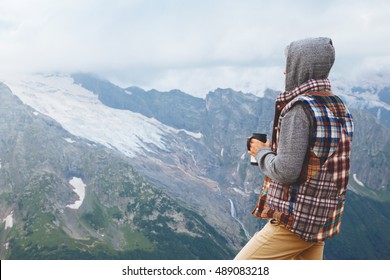 Man Drinking Hot Coffee In Thermos Mug And Looking Into The Mountains In Snow, Winter Hike, Cold Season