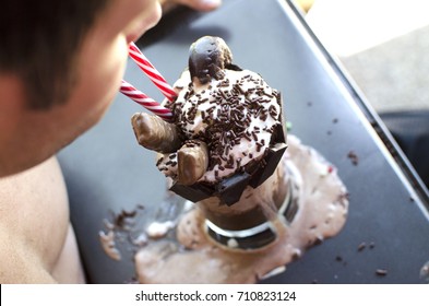 Man drinking milk shake dessert from glass as it melts.   - Powered by Shutterstock