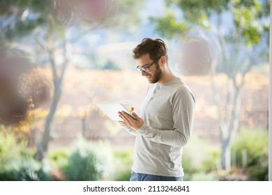 Man Drinking Orange Juice And Using Digital Tablet On Patio