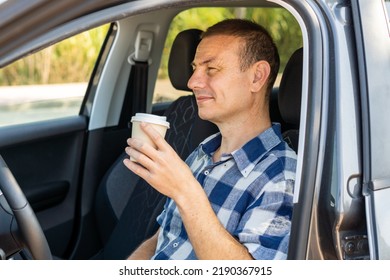 Man drinking in a paper cup inside the car.