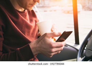 The Man Is Drinking The Soda And Sitting On The Phone In The Car