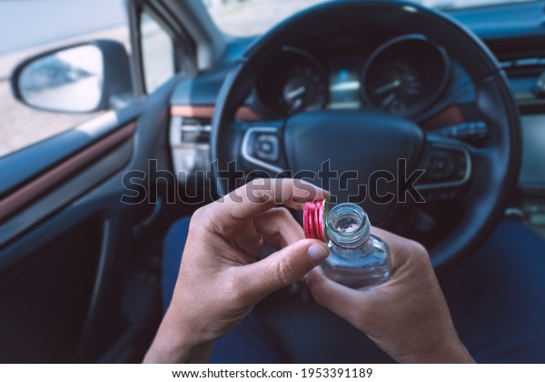 Man drinking vodka in his car. Drunk driver.\
Drinking alcohol in\
automobile