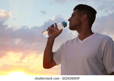 Man Drinking Water To Prevent Heat Stroke Outdoors At Sunset, Space For Text