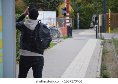Man is drinking while waiting at a tram stop