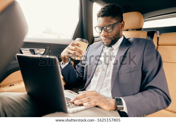 Man drinks coffee\
and works on the laptop.