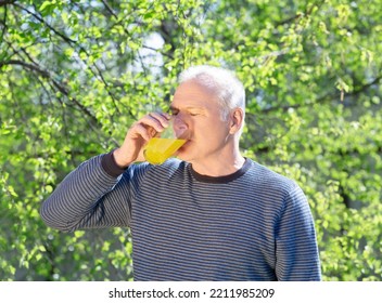 A Man Drinks A Soluble Fizzy Vitamin Drink Against The Background Of Spring Foliage