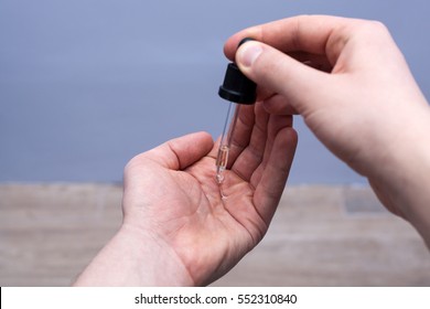 Man dripping beard oil into his palm from a pipette