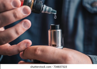 Man dripping his vape device, RDA or e-cigarette, close up, selective focus