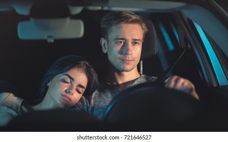 The Man Drive A Car With A Sleeping Woman. Evening Night Time