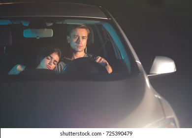 The Man Drive A Car With A Sleeping Woman. Evening Night Time