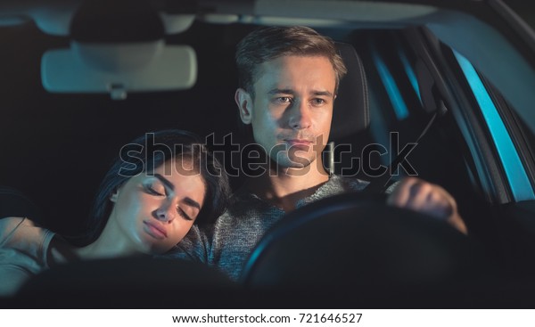 The man drive a car with a sleeping woman. evening\
night time