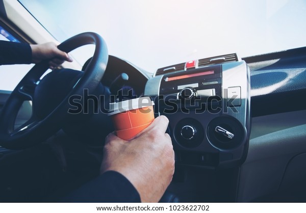 Man drive car while holding a cup of hot\
coffee - car driving sleepy or asleep\
concept