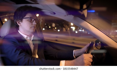 Man Driver In Black Suit And Eyeglasses Holding The Wheel. Middle Shot Of Driver At Night, Businessman In Car Driving At Night, Middle Shot