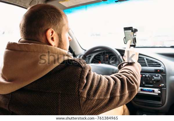 Man driver in car touching by hand smartphone\
screen with application navigation system, GPS using in\
transportation and travel concept,\
toned