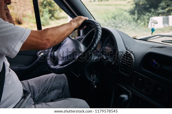 Man Driver driving a car. The driver holds the\
steering wheel.
