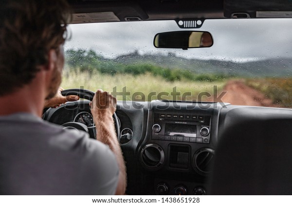Man\
driver driving off road trail path with 4x4 car on adventure trip\
travel holiday. Hawaii drive in the rain bad\
weather.