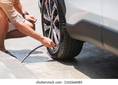 man driver hand inflating tires of vehicle, removing tire valve nitrogen cap for checking air pressure and filling air on car wheel at gas station. self service, maintenance and safety - Shutterstock ID 2162666085