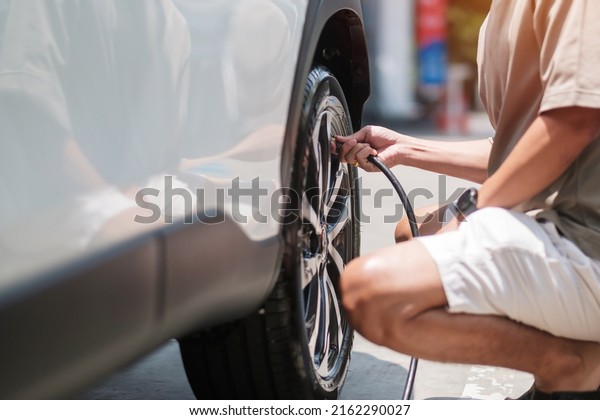 man\
driver hand inflating tires of vehicle, removing tire valve\
nitrogen cap for checking air pressure and filling air on car wheel\
at gas station. self service, maintenance and\
safety