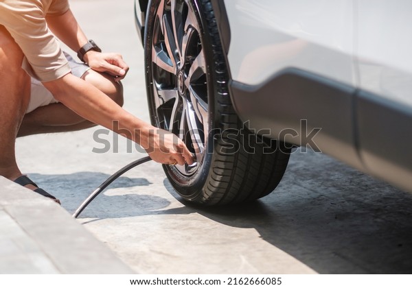 man
driver hand inflating tires of vehicle, removing tire valve
nitrogen cap for checking air pressure and filling air on car wheel
at gas station. self service, maintenance and
safety