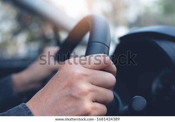 Man\
driver holding steering wheel inside a car, close\
up