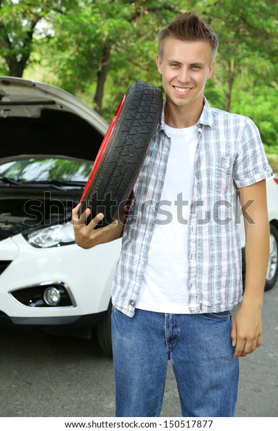 Man driver holding tire\
on shoulder