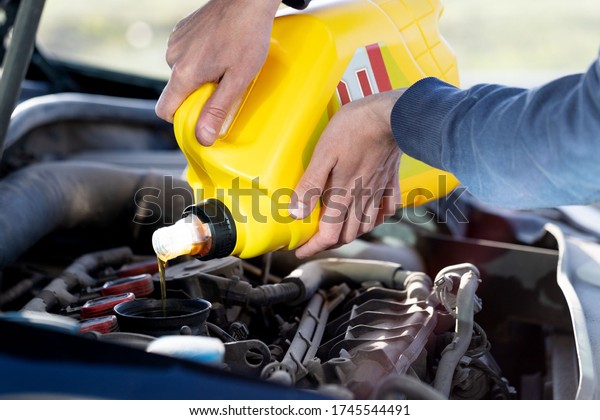 Man driver pouring and refueling oil quality\
into the engine motor car, close\
up.