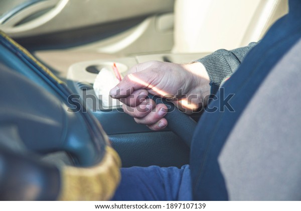 Man driver pulling\
the hand brake in car