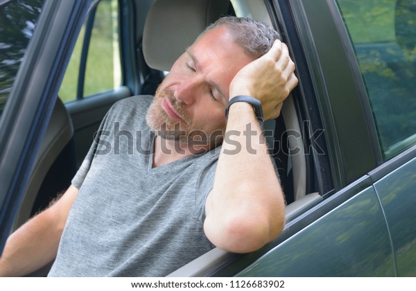 Man\
driver is resting in the car during a travel\
break