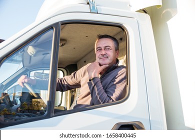 A Man Driver Is Sitting In The Cab Of A Modern Truck.