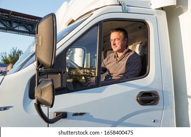 A Man Driver Is Sitting In The Cab Of A Modern Truck.