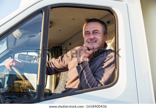A man
driver is sitting in the cab of a modern
truck.