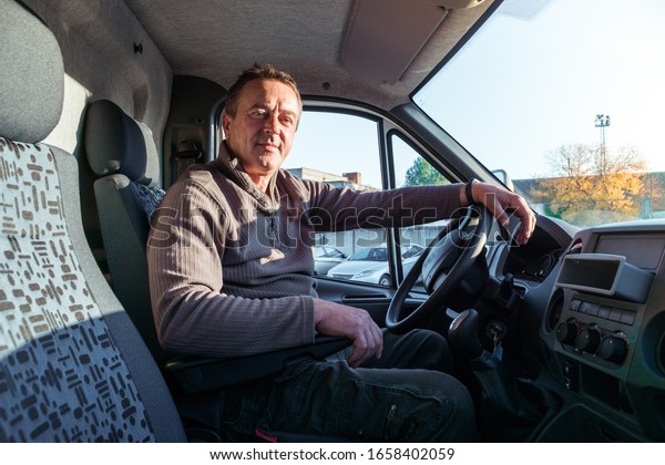 A man\
driver is sitting in the cab of a modern\
truck.