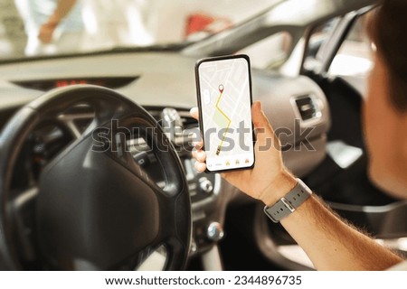 Man driver sitting in front sit in the car, holding mobile phone with map gps navigation on gadget screen, unrecognizable guy checking location destination, travelling alone by auto