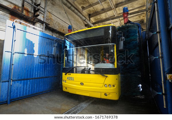 Man driver sitting in the trolleybus cabin while\
it washing at the auto wash brushes working, trolley bus depot.\
March 11, 2020. Kiev,\
Ukraine