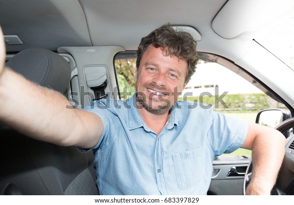 man Driver Smiling Sitting in Driver Seat with\
make a selfie with\
smartphone