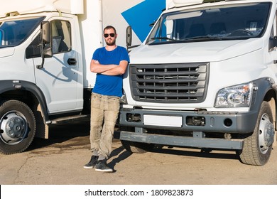 A man driver stands near the truck;