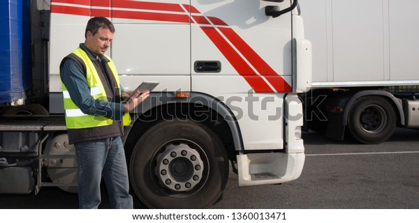 man driver with tablet computer in front of delivery\
logistics truck 
