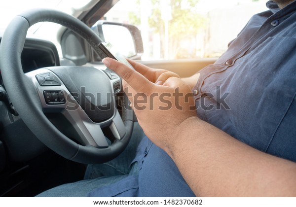 Man driver using mobile phone when driving car\
on road. people hand holding smart phone driving car, dangerous\
accident concept.