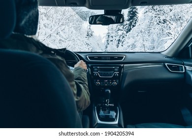 Man Drives A Car On Snow Winter Road. Rear View From The Car, Man Driving In Snow Winter Forest.