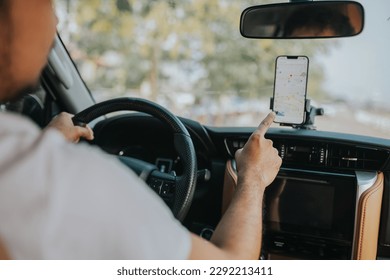 A man drives a car using a GPS navigation system on his mobile phone while driving, to find his destination. - Powered by Shutterstock