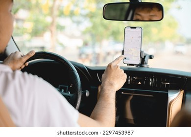 A man drives a car using a GPS navigation system on his mobile phone while driving, to find his destination. Transportation with technology concept.