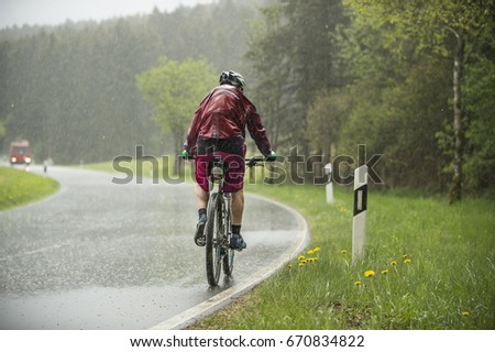 Man drives on the bicycle in the rain 